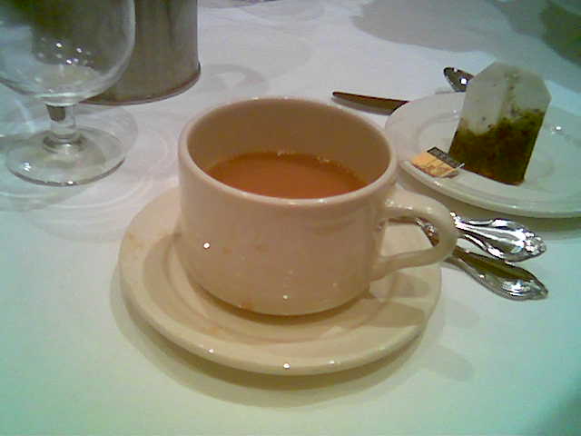 there is a cup of tea and silverware on the table