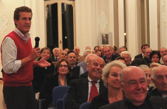 a man in red jacket talking to audience