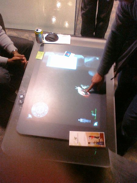 several people standing around the table with a screen on it
