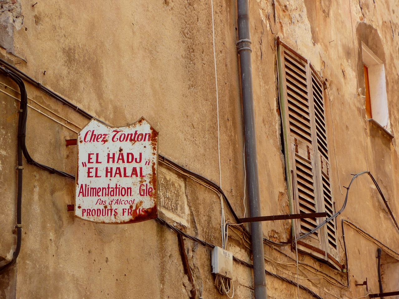 the side of an old building with a sign in spanish hanging from it
