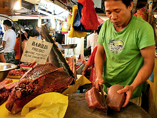 a man in a green shirt slicing meat
