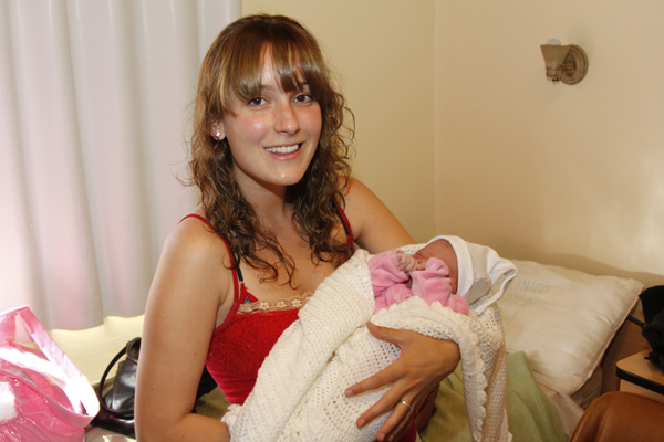 a smiling young woman is holding a baby