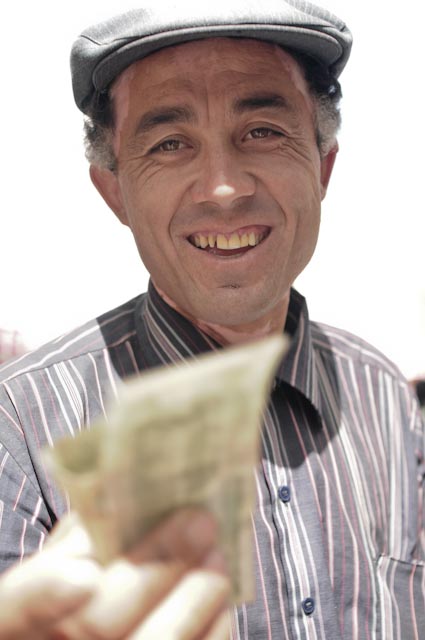an elderly man is smiling while he is holding money