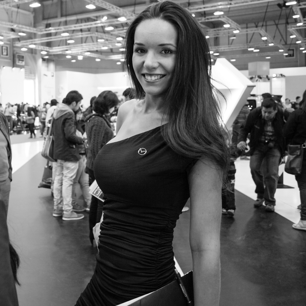 a woman in a dress smiles while standing with a folder