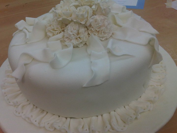 a white cake with ruffled bottom, covered in flowers