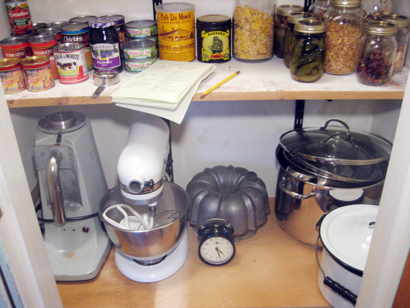 a kitchen pantry has lots of food and cooking implements on shelves