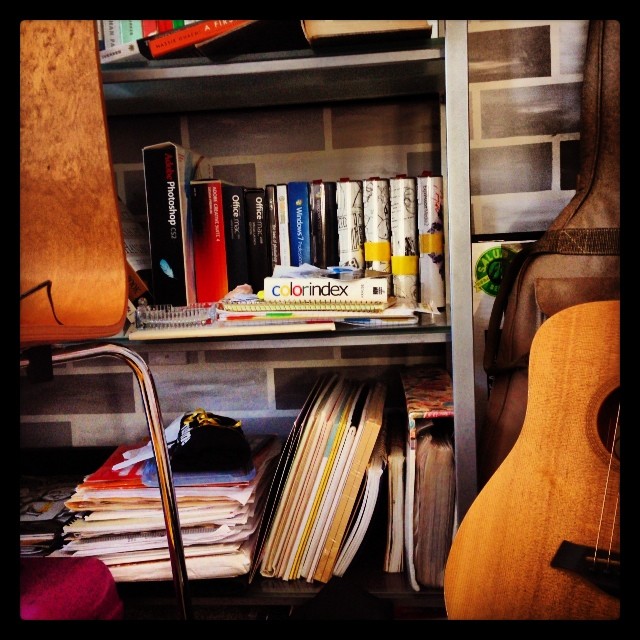 a guitar and a book shelf with books
