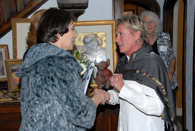 two women congratulate each other in front of pictures