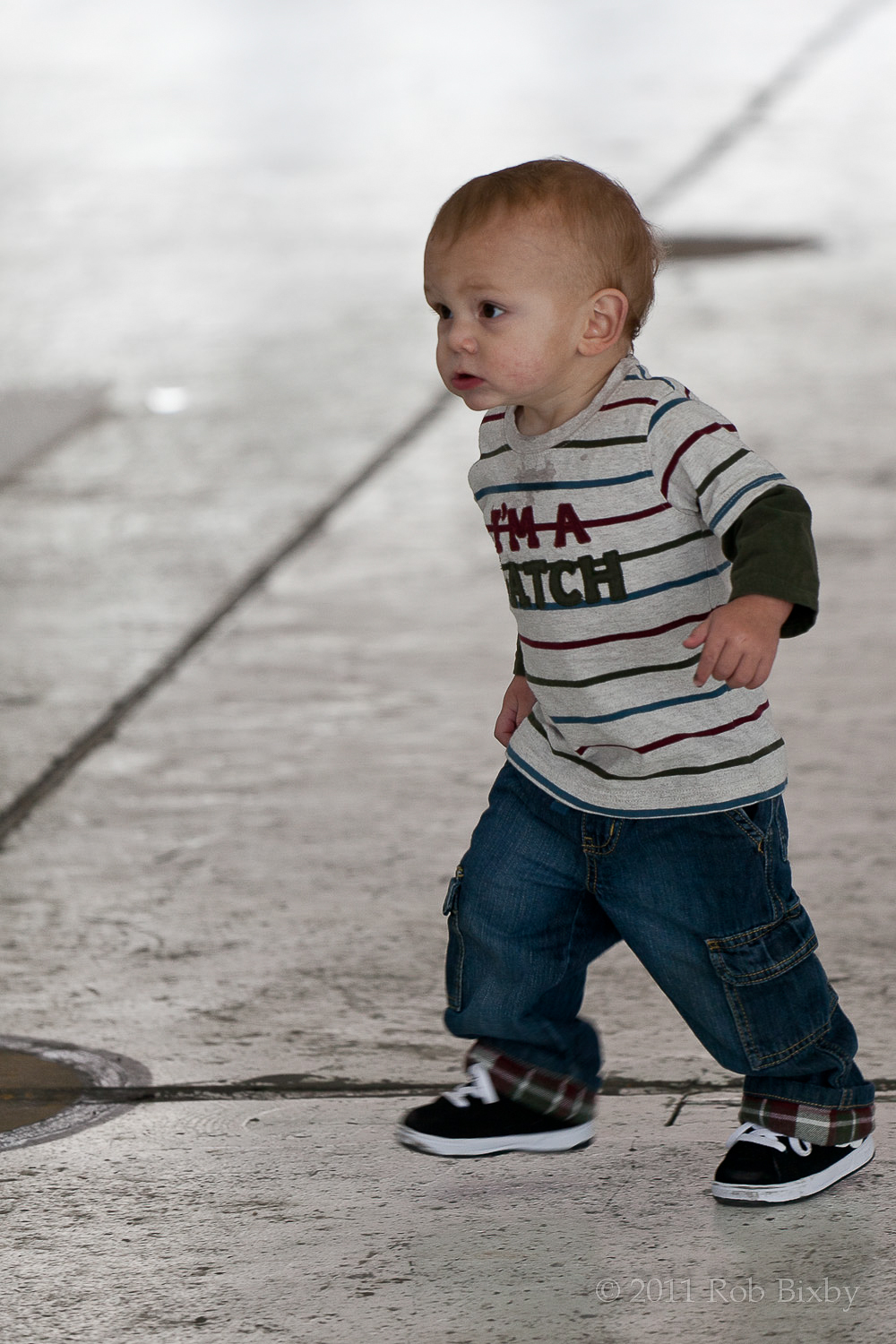 a toddler is walking on a cement floor