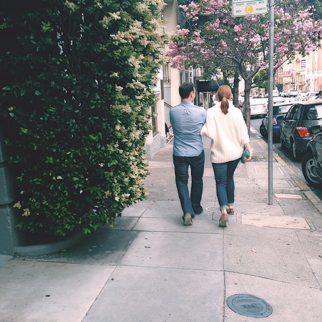 the man and woman are walking on a city sidewalk