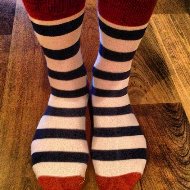 a persons foot wearing striped socks in front of a wooden floor
