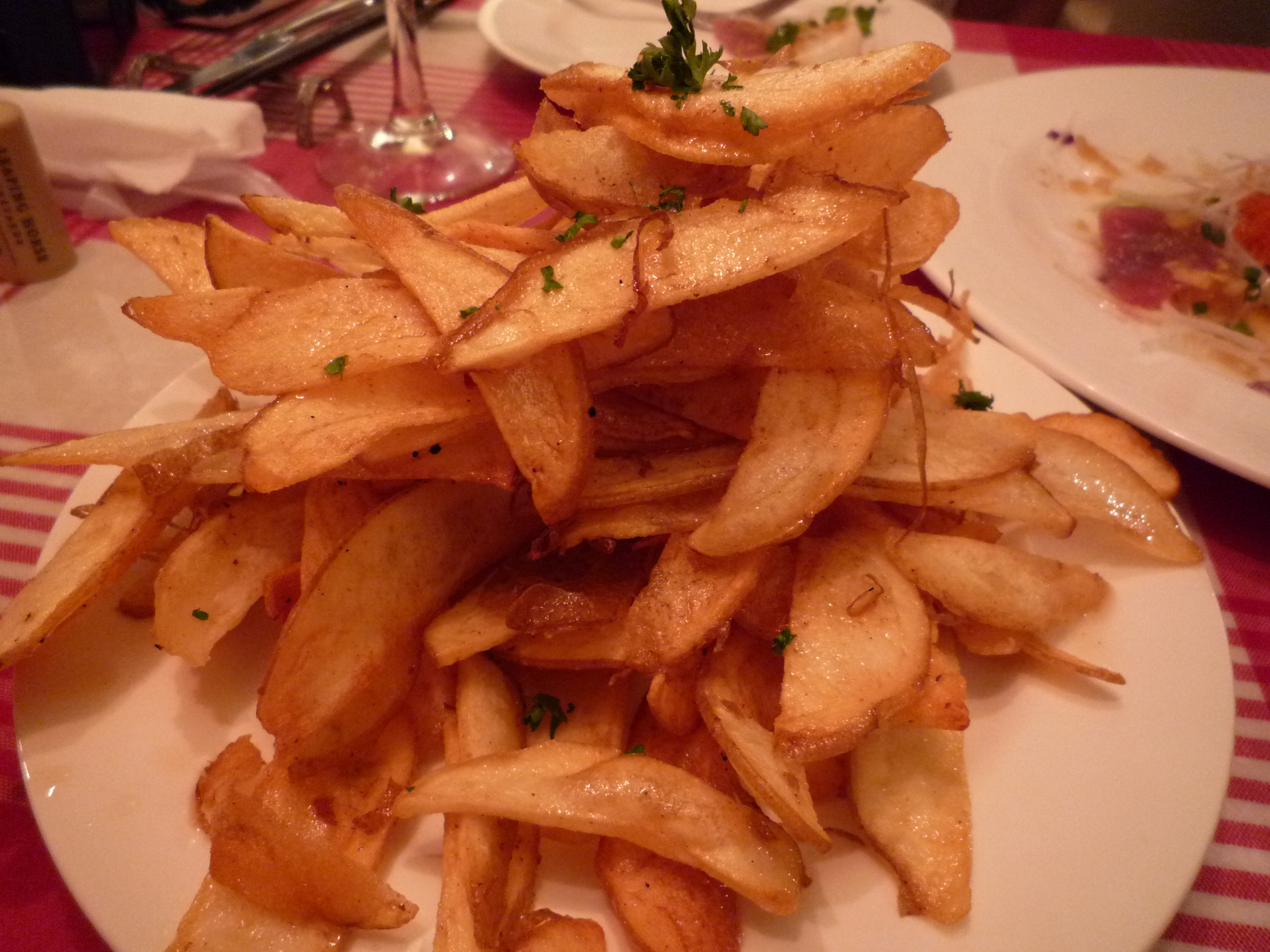 a pile of fried french fries on a white plate