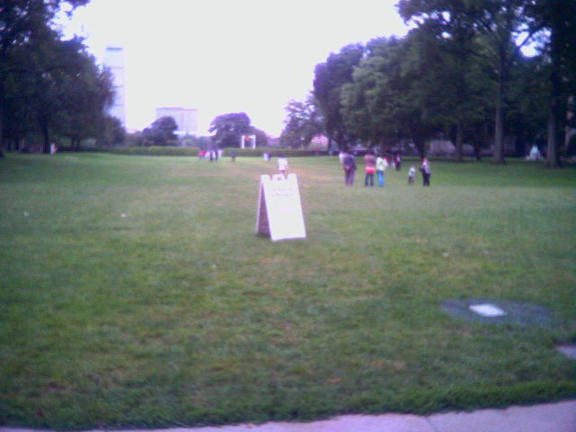 children playing frisbee in the park with an open sign
