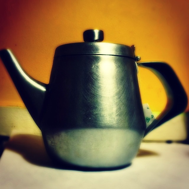 the teapot has an elegant top and a large handle