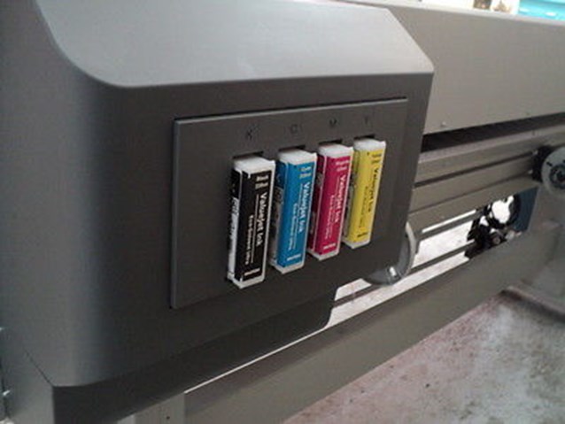 there is a multi - colored can of ink and several books on the printer