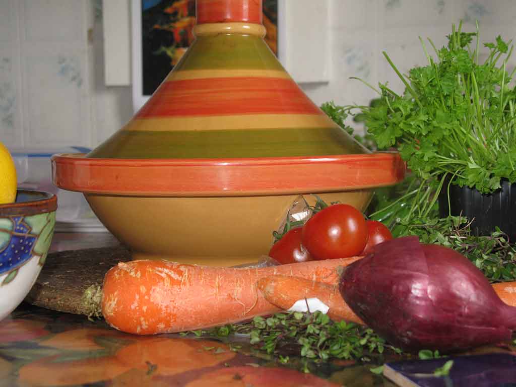 the colorful vase and vegetables are on the counter top