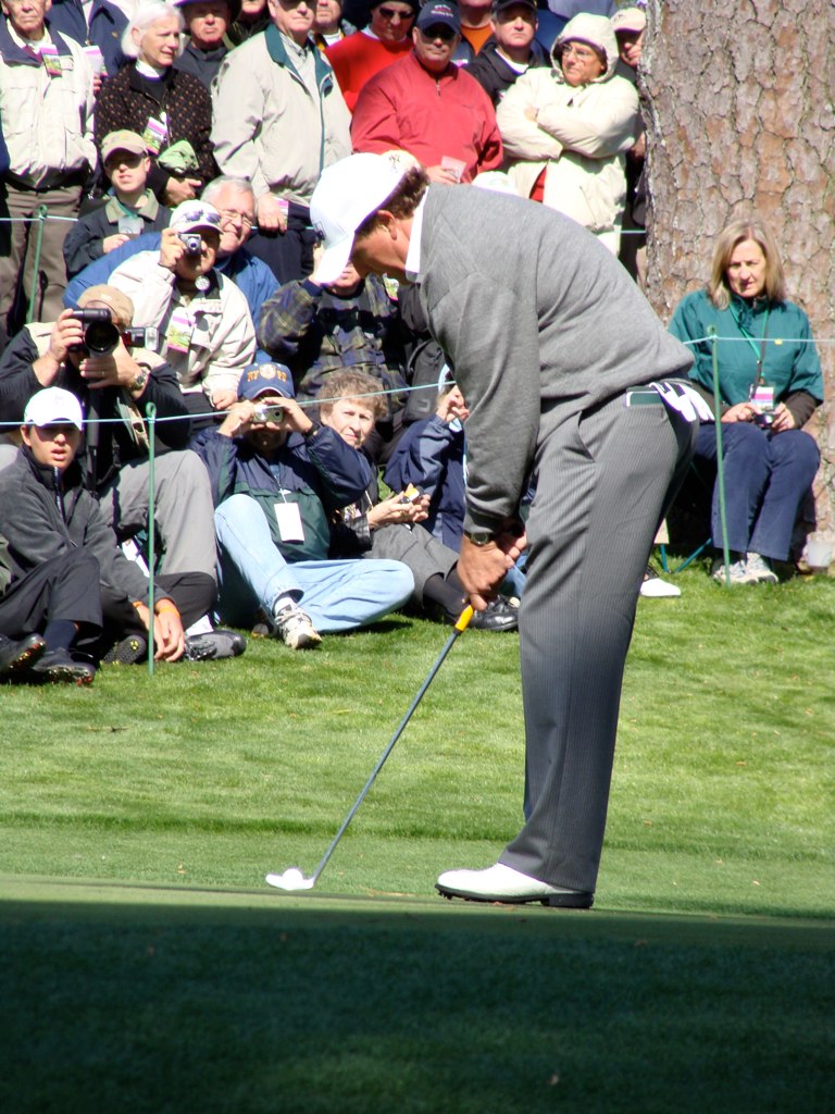 a golf player in grey suit hitting golf ball