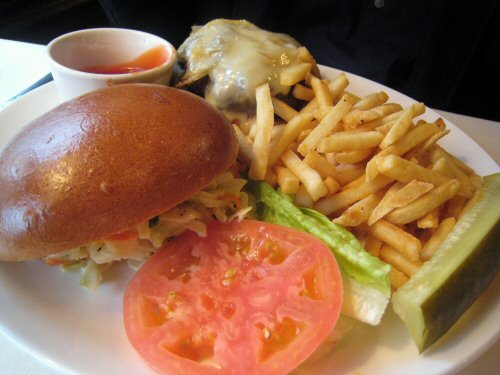 a hamburger, tomato, fries and some condiments are on the plate