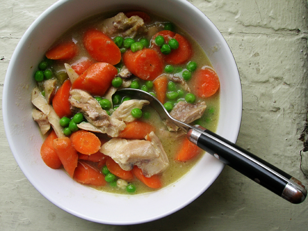 a bowl of vegetables and meat with a spoon