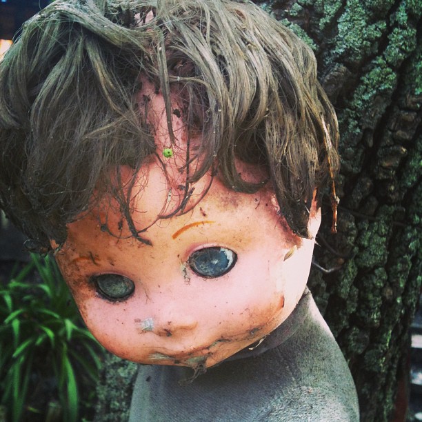 a worn doll that has been placed on a tree