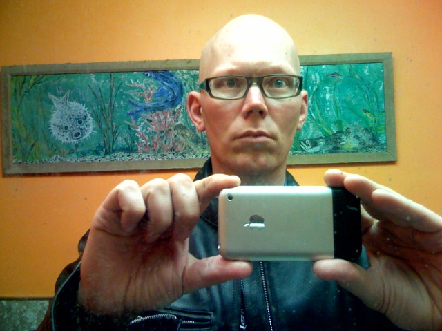 man with glasses holding an iphone in front of his face