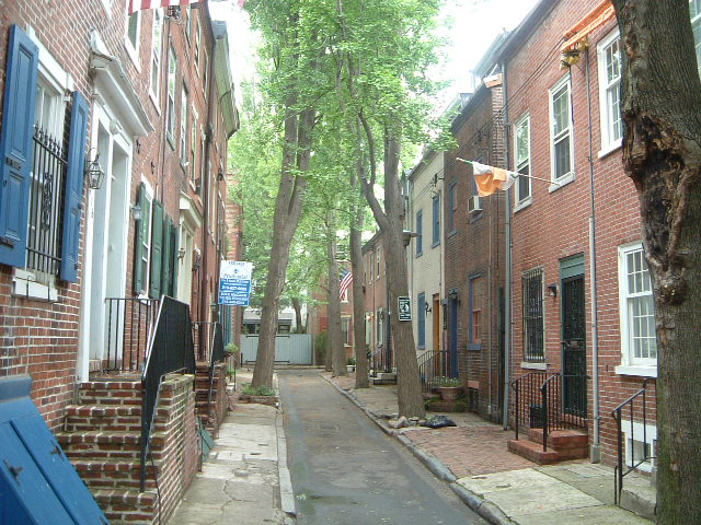a back street with brick buildings and windows next to trees