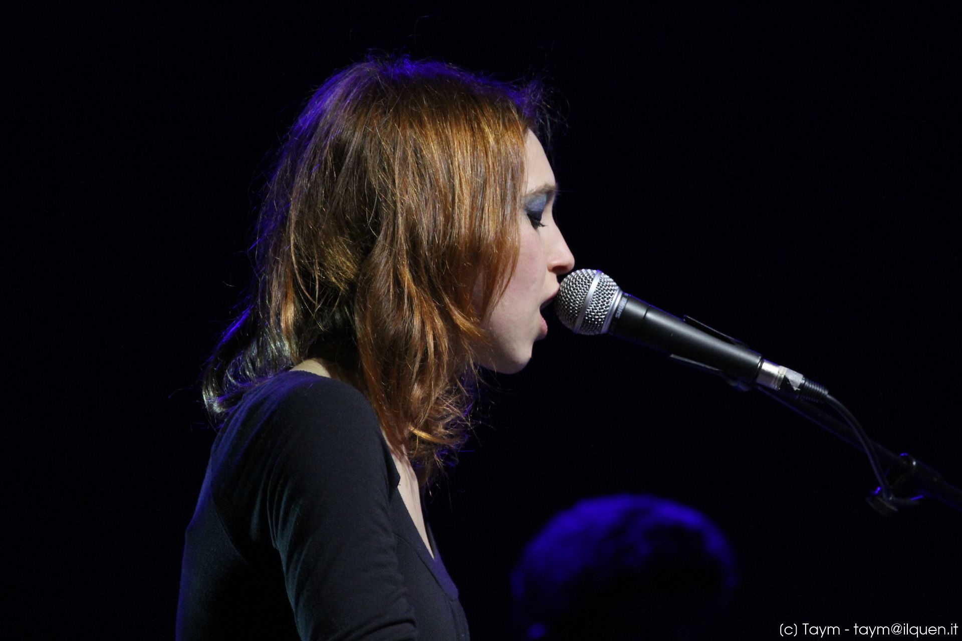 the woman is singing into her microphone on stage