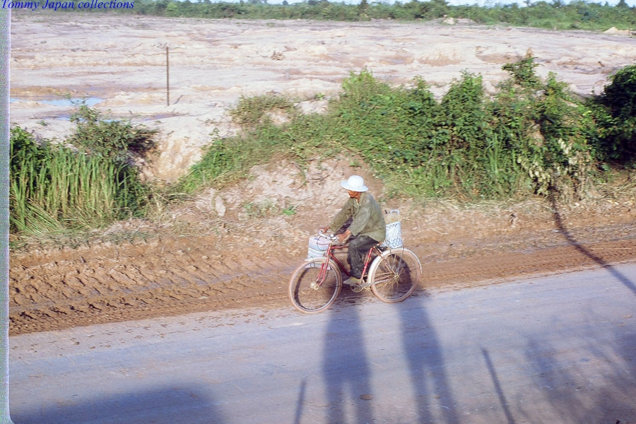 man riding his motorcycle down the road while standing in the dirt