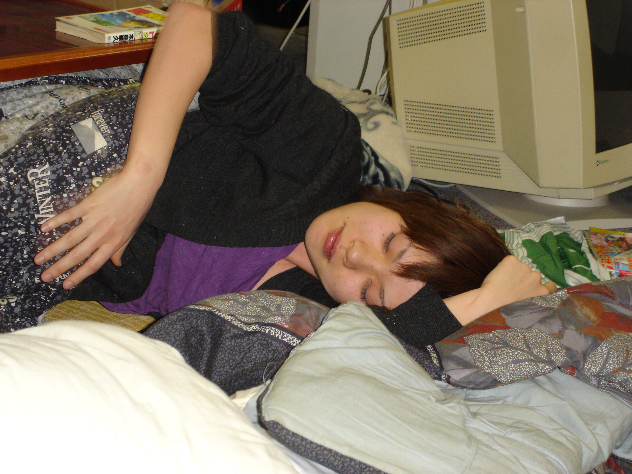 a woman laying on a bed next to a computer monitor