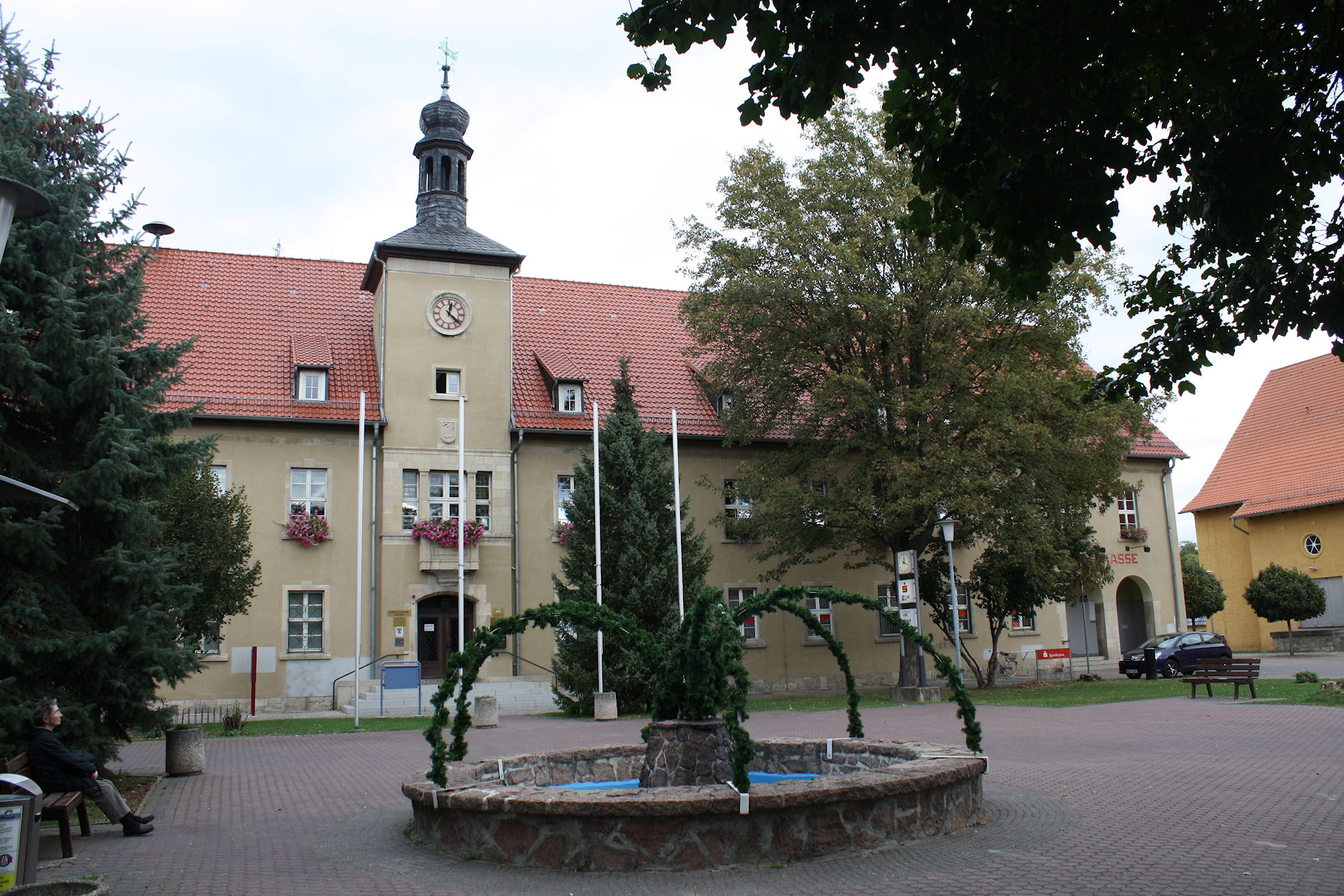 a large yellow building has trees and plants in front