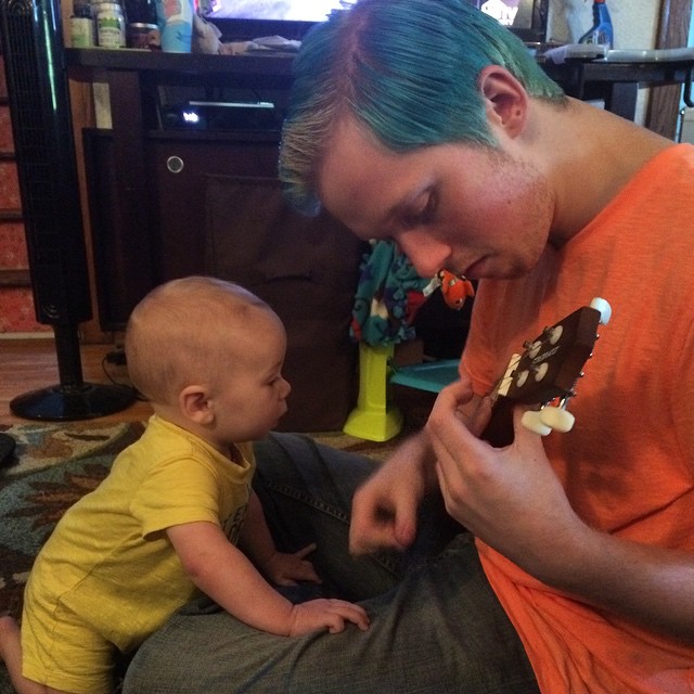 the man is playing with his child while they have an electronic guitar