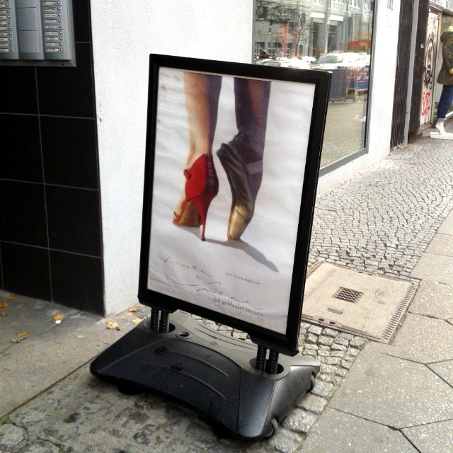 a poster of a woman's shoes on display on a sidewalk