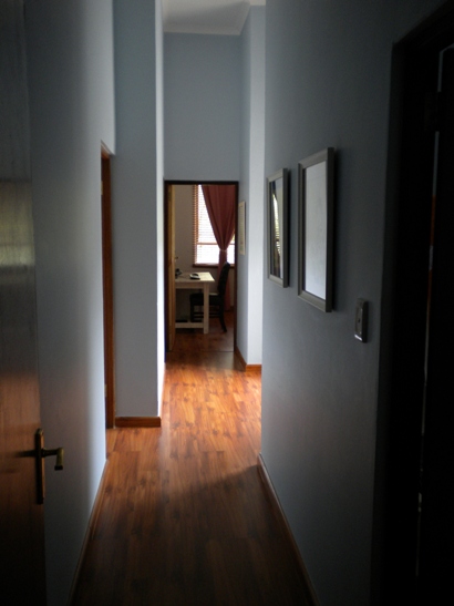 an empty hallway with wood flooring and artwork on the wall