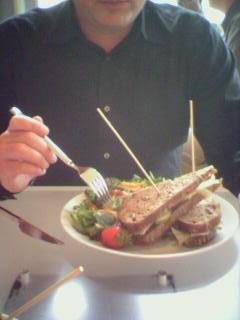 a man is sitting at the table with a salad in his hand