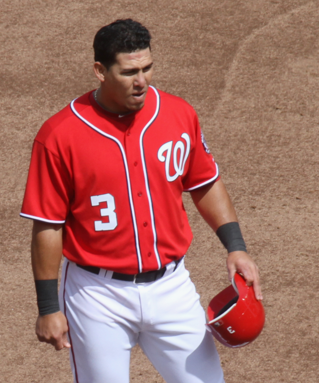 a baseball player holding a red helmet and glove