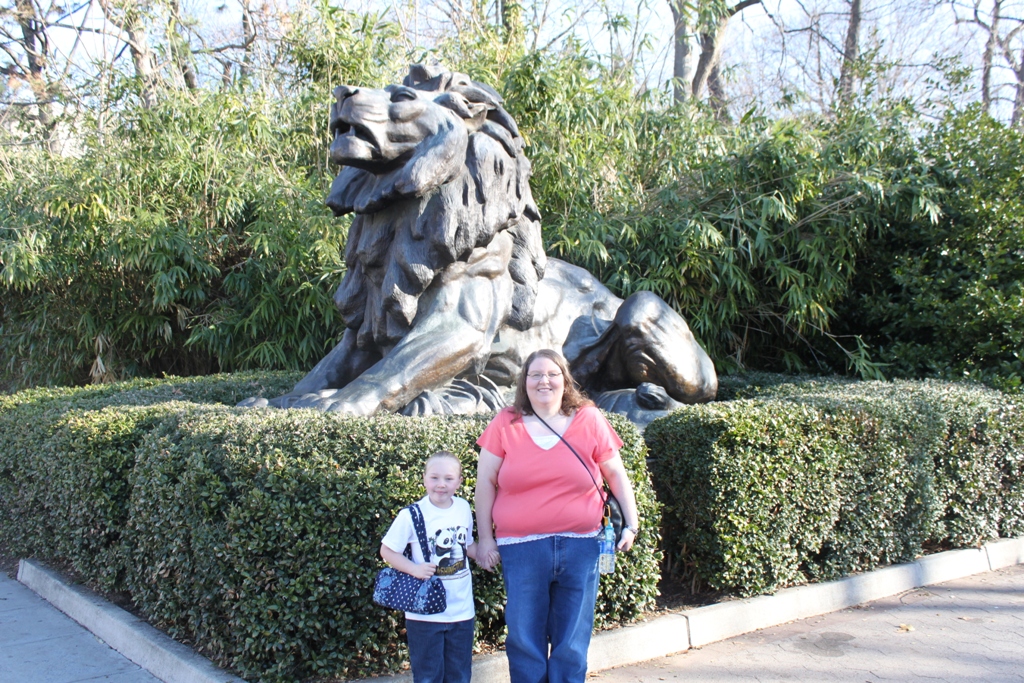 a mother and son standing next to a big statue