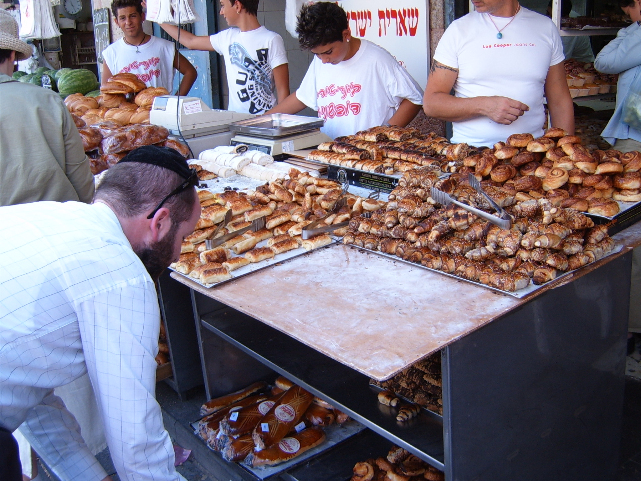 people browse the selection of baked goods for sale at a market