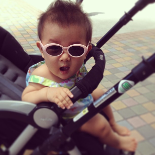 a baby wearing sunglasses riding a stroller