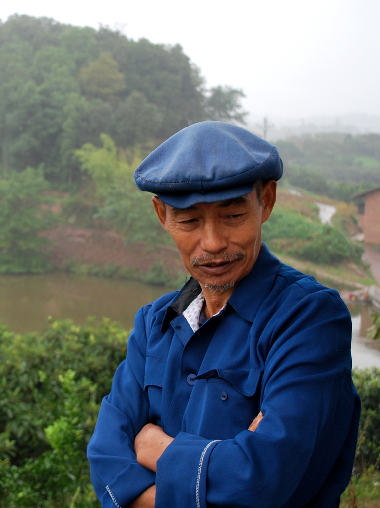 a man in blue shirt and hat next to trees