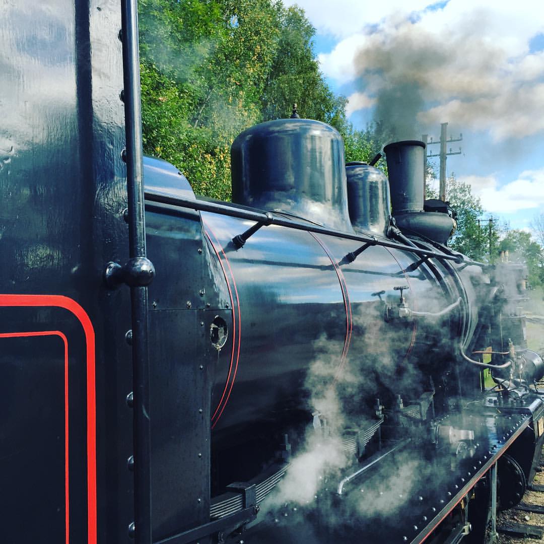 an old style steam train is blowing smoke on the track