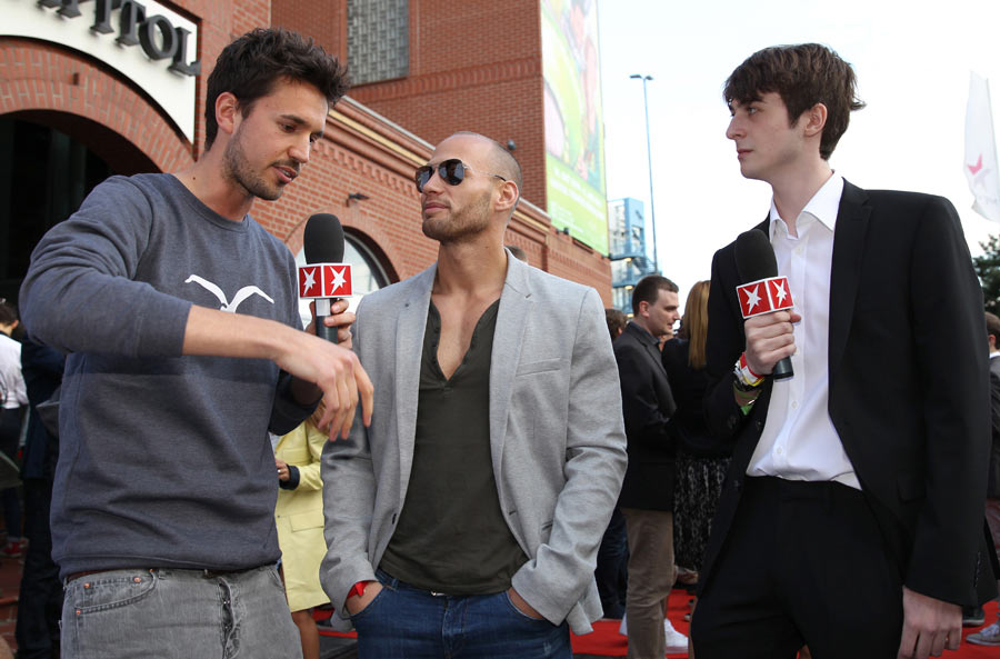 two men talking and one is holding a microphone