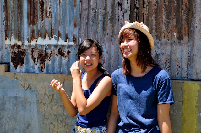 two girls are smiling while posing against a metal wall