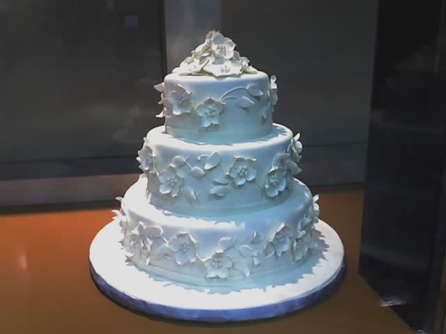 a four tier white cake with blue flowers