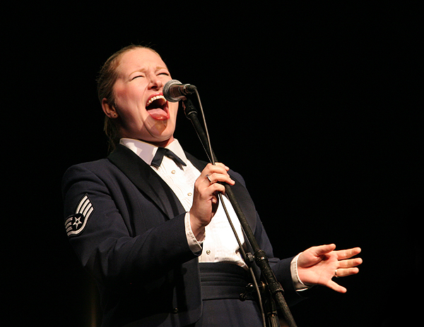 woman in suit singing into a microphone at night