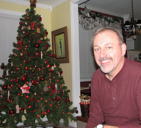 a man smiling in front of a christmas tree