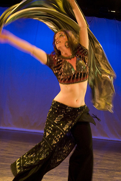 the belly dancer is dancing with her flowing black shawl