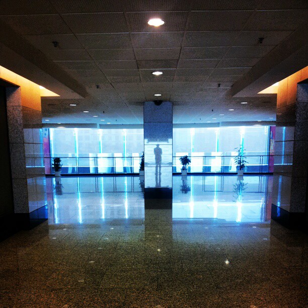 a very empty and dimly lit lobby with a few people standing