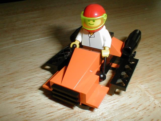 a lego man is sitting on top of the back of a track