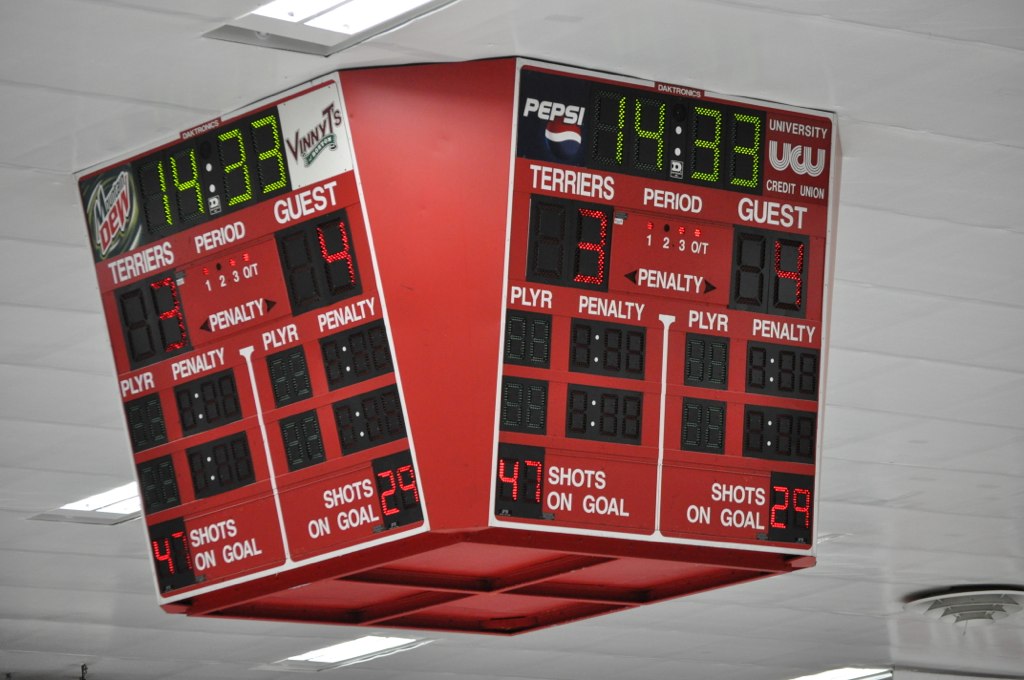 two clocks are placed in a ceiling at a basketball game