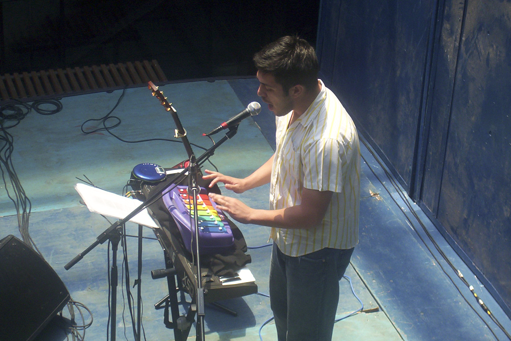 a man with microphone in his hand on stage next to musical instrument